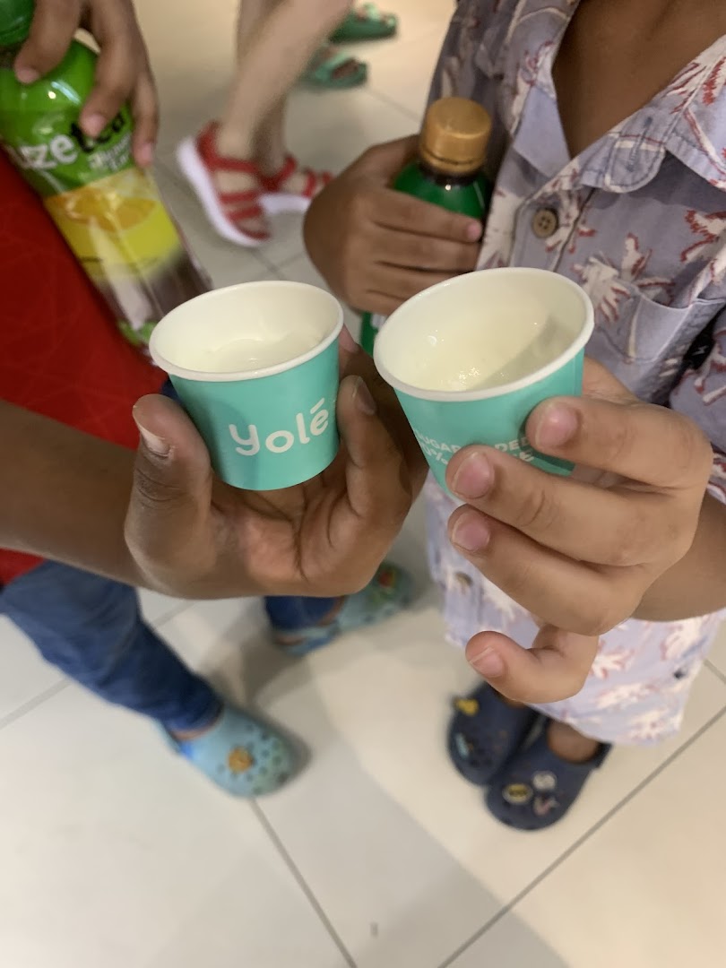 Two small Yolé cups held by children, with drinks and people in the background.
