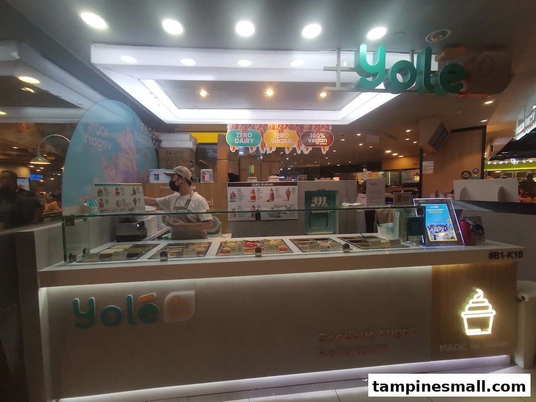 A Yolé frozen yogurt counter with an employee, showcasing healthy options like zero sugar and vegan choices.