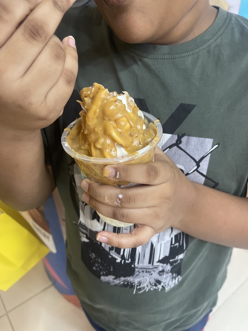 A person enjoys a delicious Yolé frozen yogurt topped with a rich, creamy sauce.