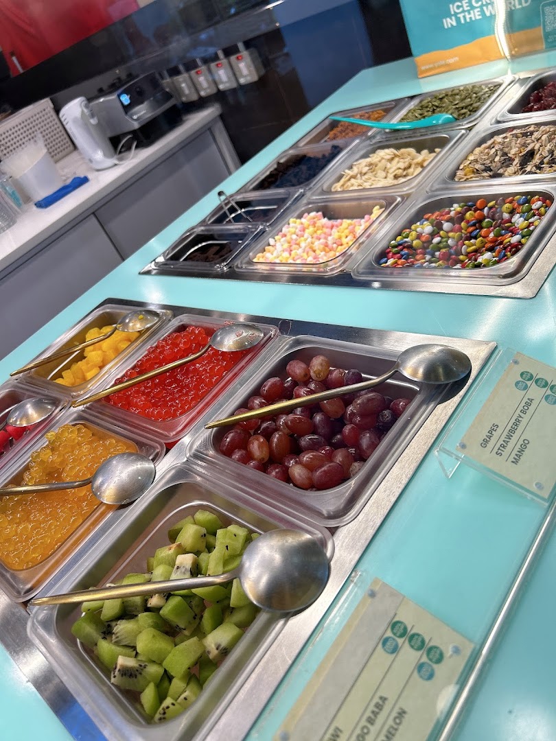 A vibrant display of fresh fruits, candies, and various toppings at a frozen yogurt shop.