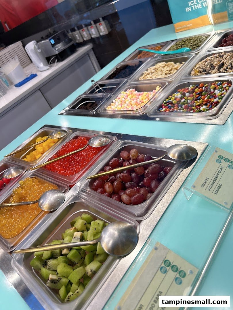 A vibrant display of fresh fruits, candies, and various toppings at a frozen yogurt shop.