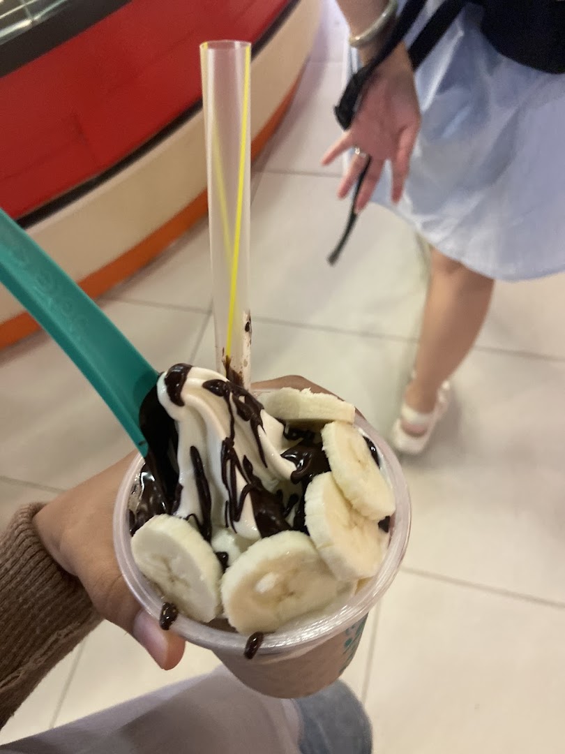 A close-up of a delicious Yolé frozen yogurt topped with banana slices and chocolate sauce.
