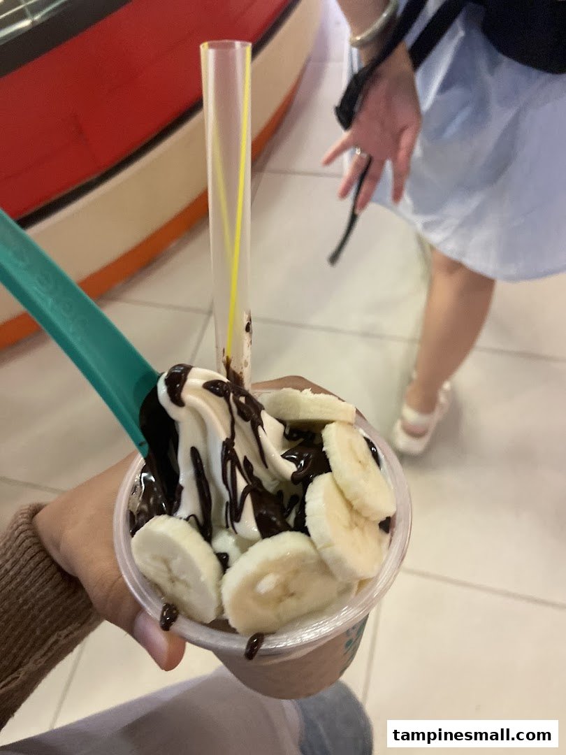 A close-up of a delicious Yolé frozen yogurt topped with banana slices and chocolate sauce.