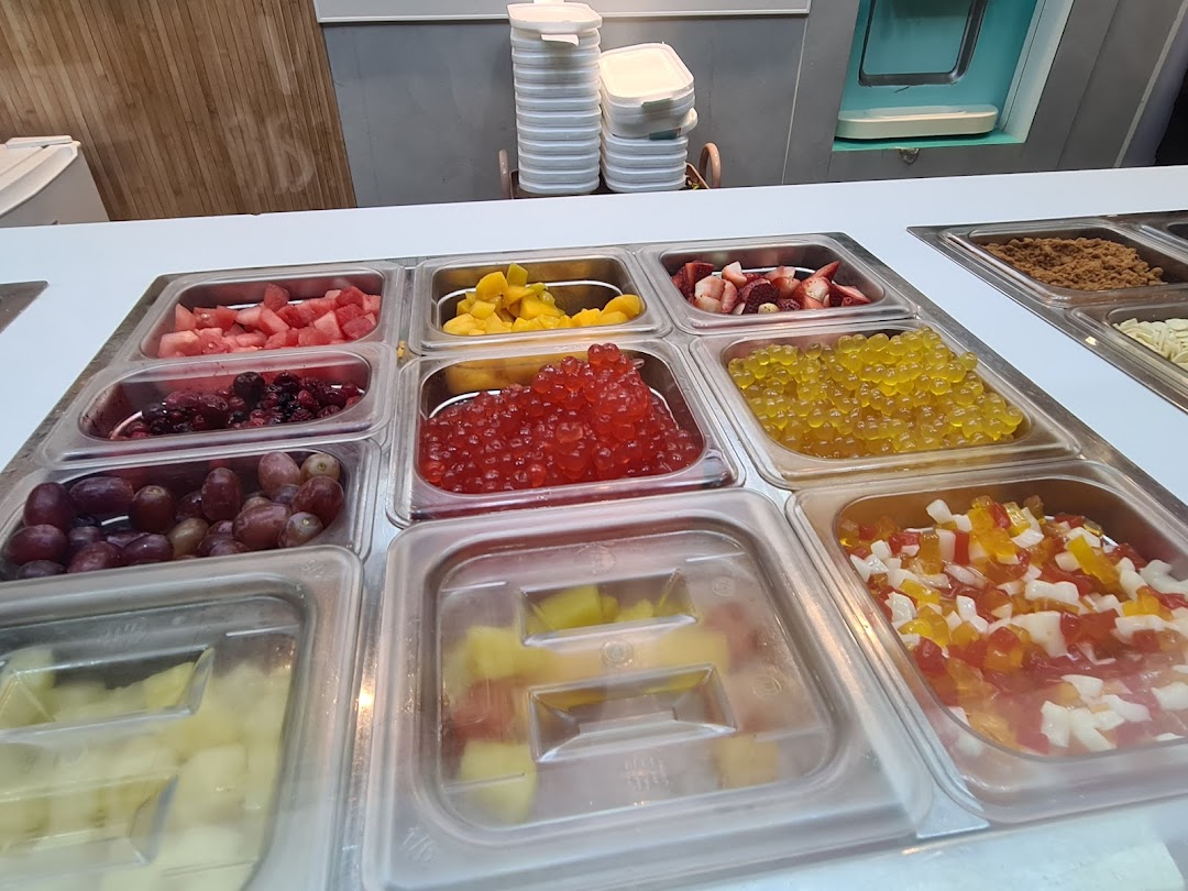 A vibrant display of fresh fruits, popping boba, and other toppings for frozen yogurt.