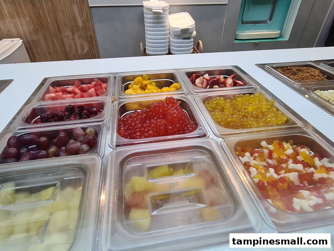 A vibrant display of fresh fruits, popping boba, and other toppings for frozen yogurt.