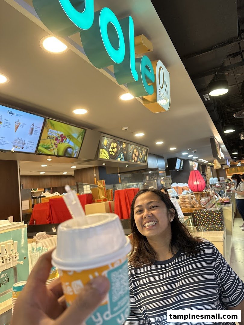 A customer holds a Yolé frozen yogurt cup inside the shop, with the brand's signage visible.