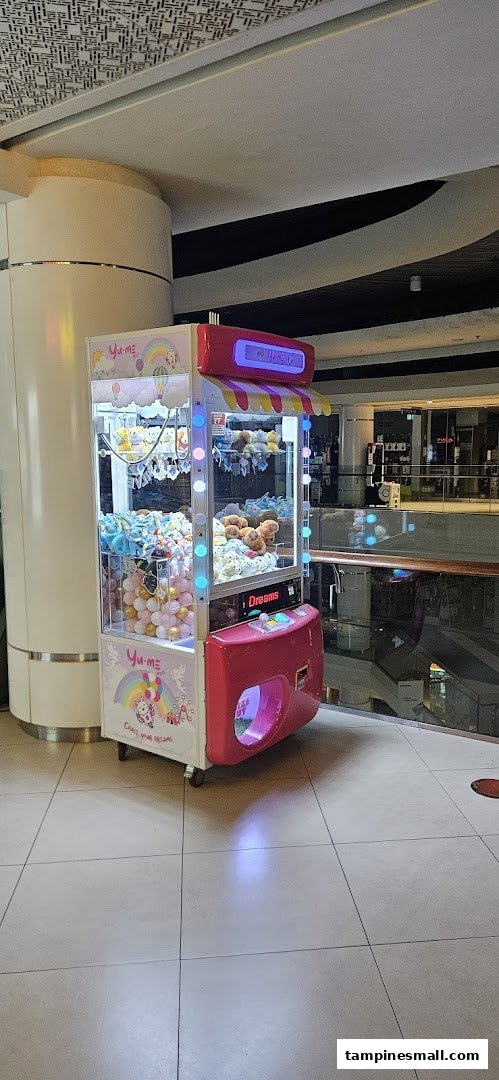 A vibrant Yume Claw machine filled with plush toys and prize balls, located in a shopping mall.