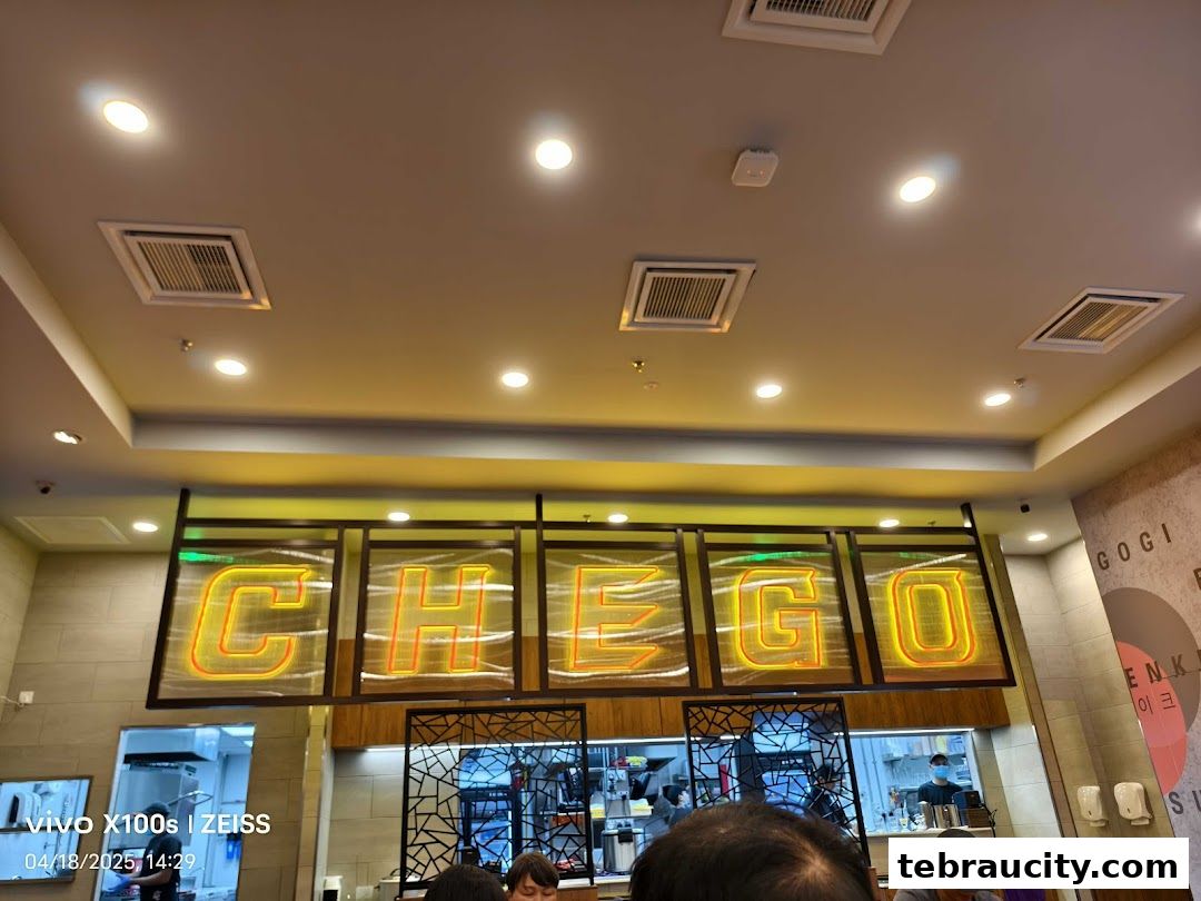 Interior view of Chego Korean BBQ with illuminated signage and kitchen staff visible.