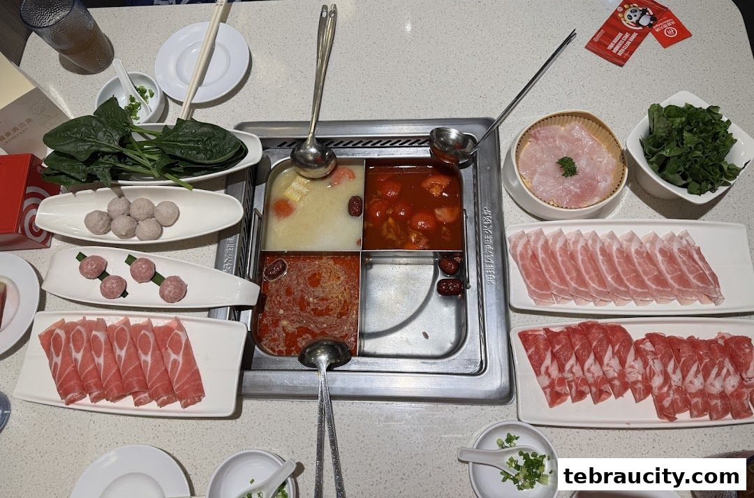 A table laden with various ingredients for hot pot, including meats, meatballs, and vegetables.