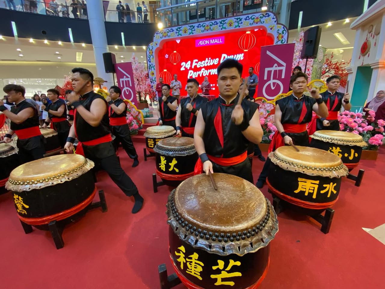 A wide shot of the crowd gathered to watch the festive drum performance.