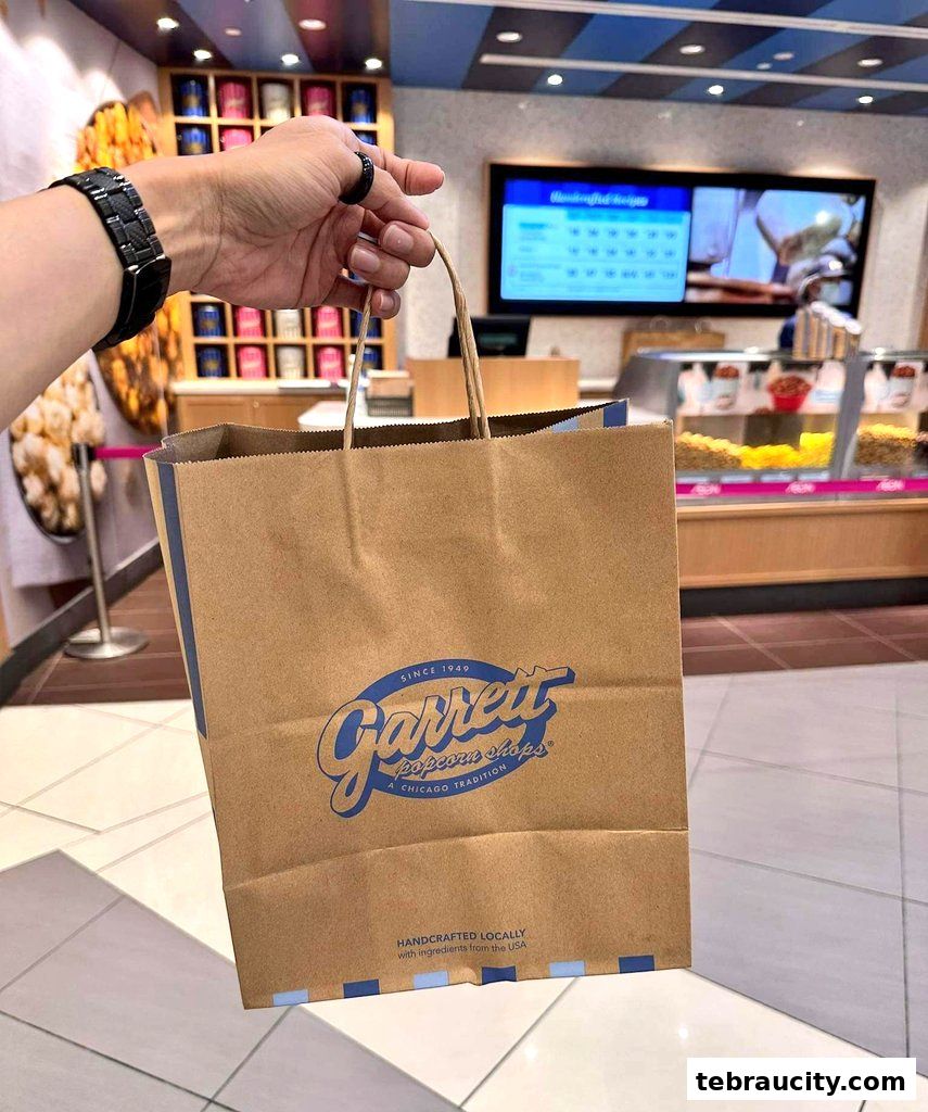 A person holds a Garrett Popcorn Shops paper bag inside the store.