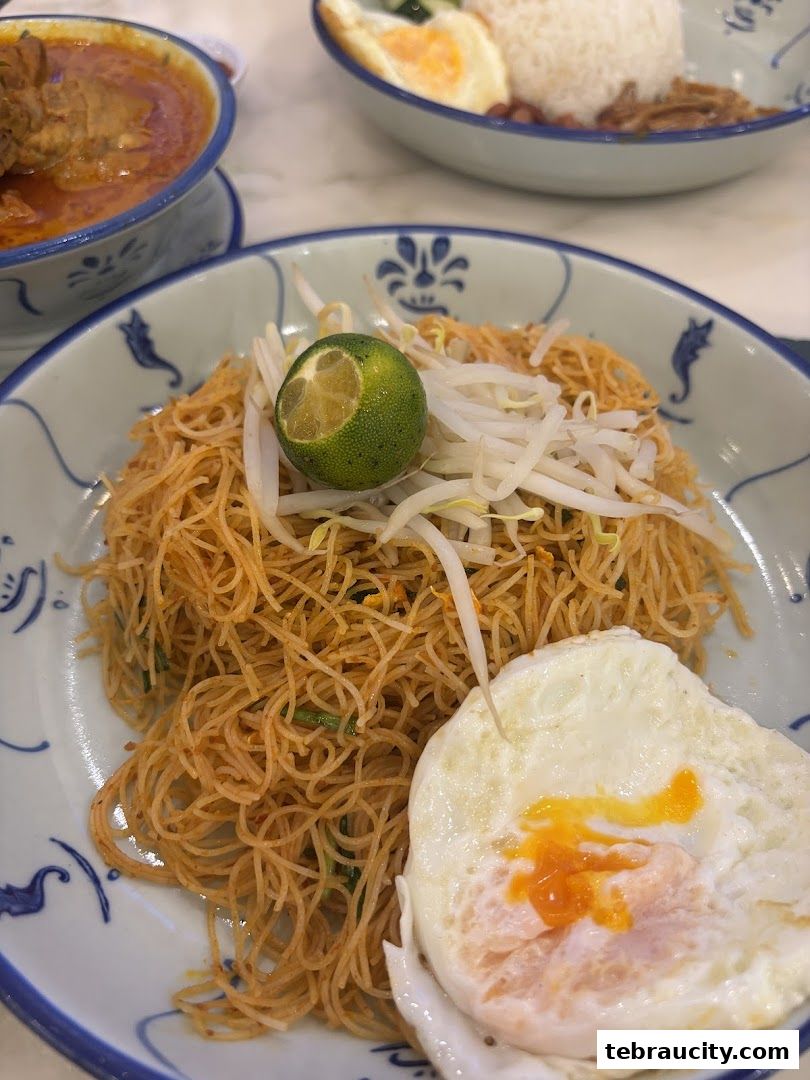 A close-up of a delicious noodle dish with a fried egg and lime.