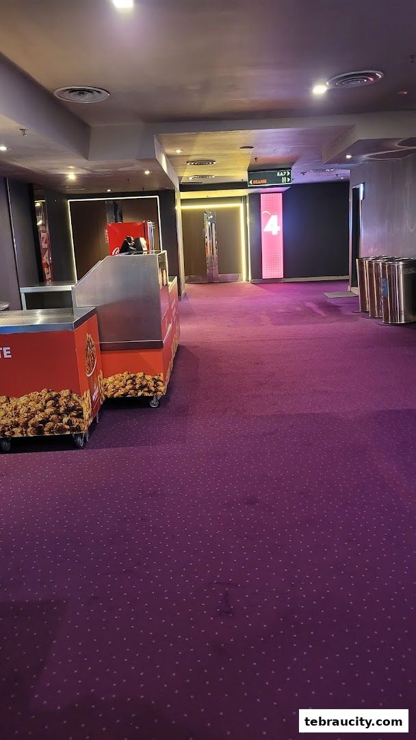 A cinema hallway with a popcorn stand and illuminated signs.