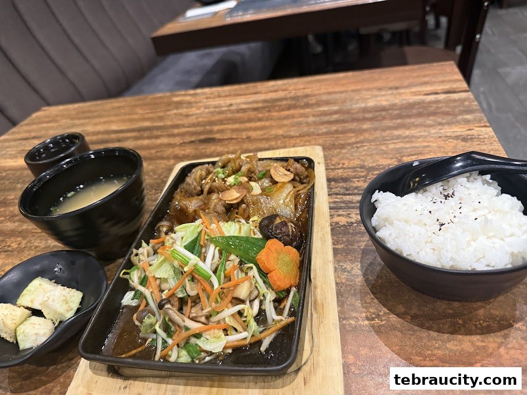 A Japanese meal featuring stir-fried meat and vegetables, rice, and miso soup.