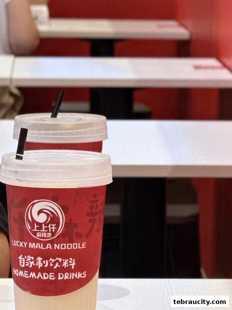 Two red cups with white lids and straws from Lucky Mala Noodle.