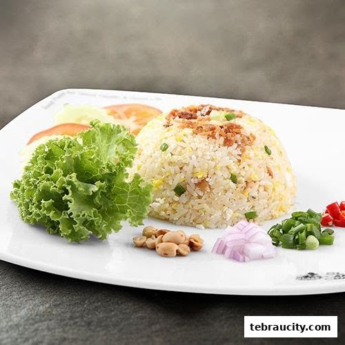 A plate of fried rice with garnishes including lettuce, tomatoes, peanuts, onions, and chili.