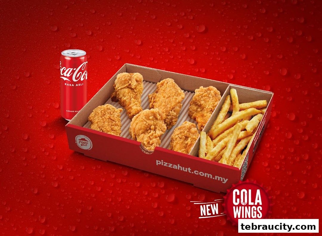 A box of crispy fried chicken wings and french fries with a can of Coca-Cola.