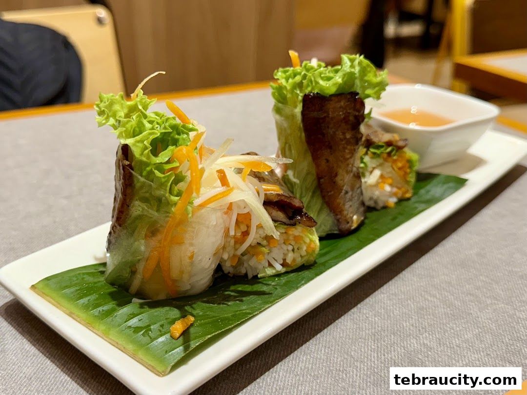 Fresh Vietnamese spring rolls with lettuce, carrots, and meat served on a banana leaf with dipping sauce.