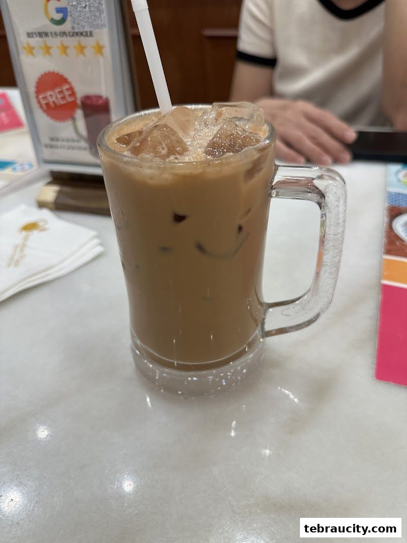 A refreshing iced coffee served in a glass mug with a straw.