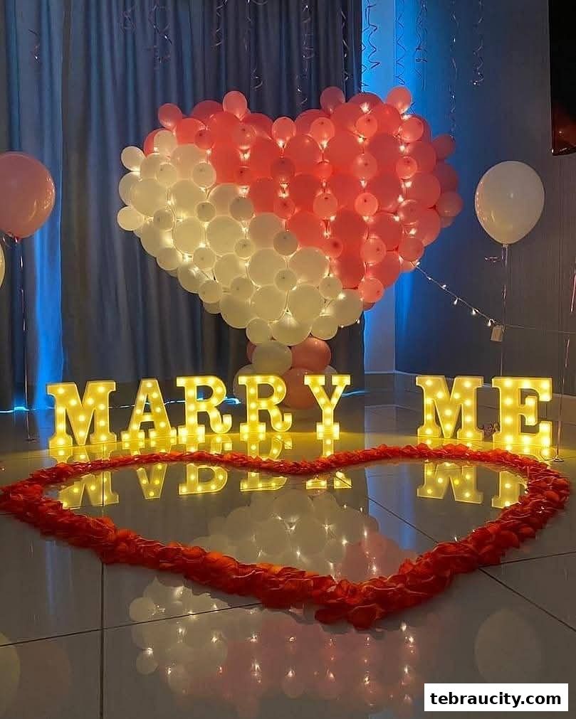 A romantic proposal setup with illuminated 'MARRY ME' letters and heart-shaped balloon decor.