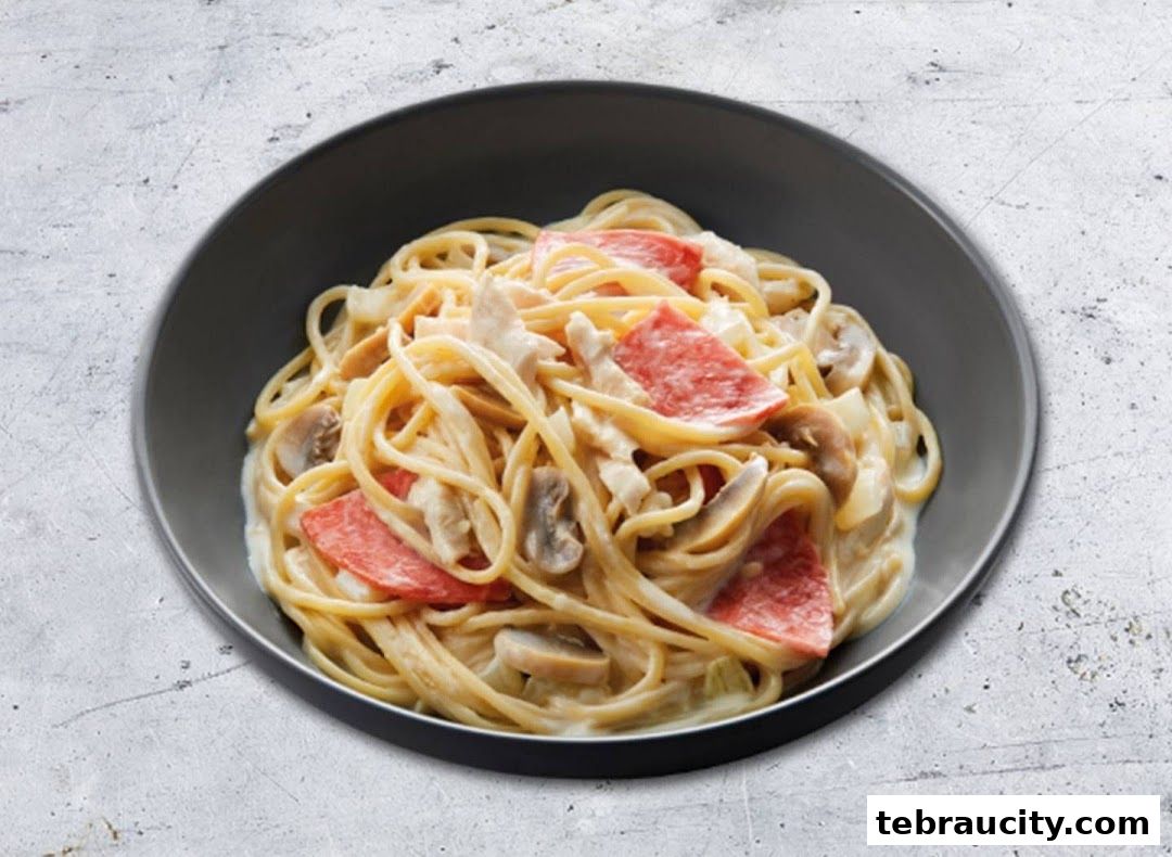 A bowl of creamy spaghetti with mushrooms and sliced meat.
