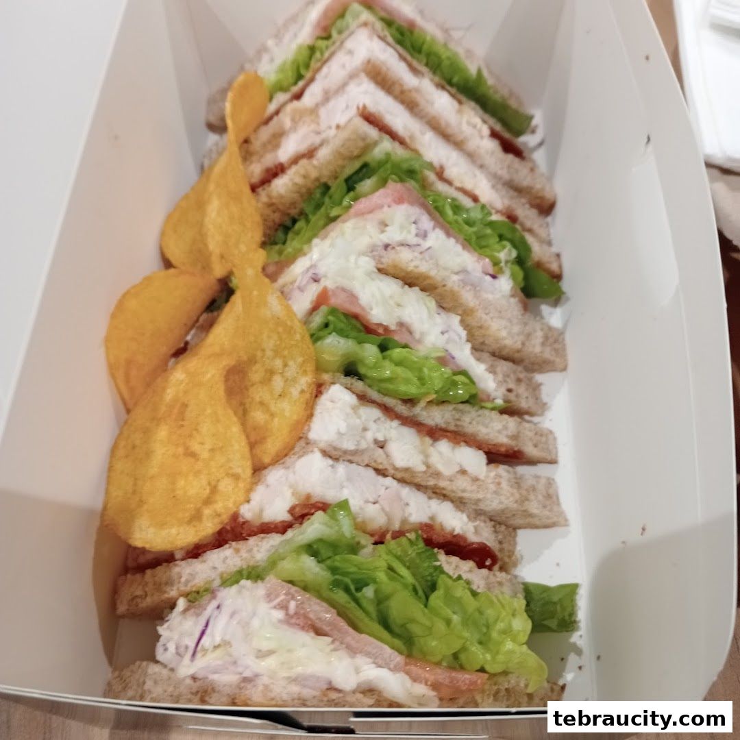 A box filled with freshly made sandwiches and potato chips.