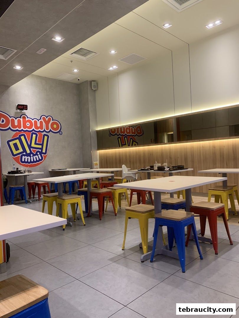 Interior of a DubuYo Mini restaurant with tables and colorful stools.