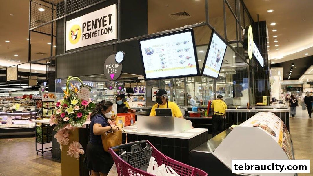 A food stall with staff serving customers and a digital menu displayed overhead.