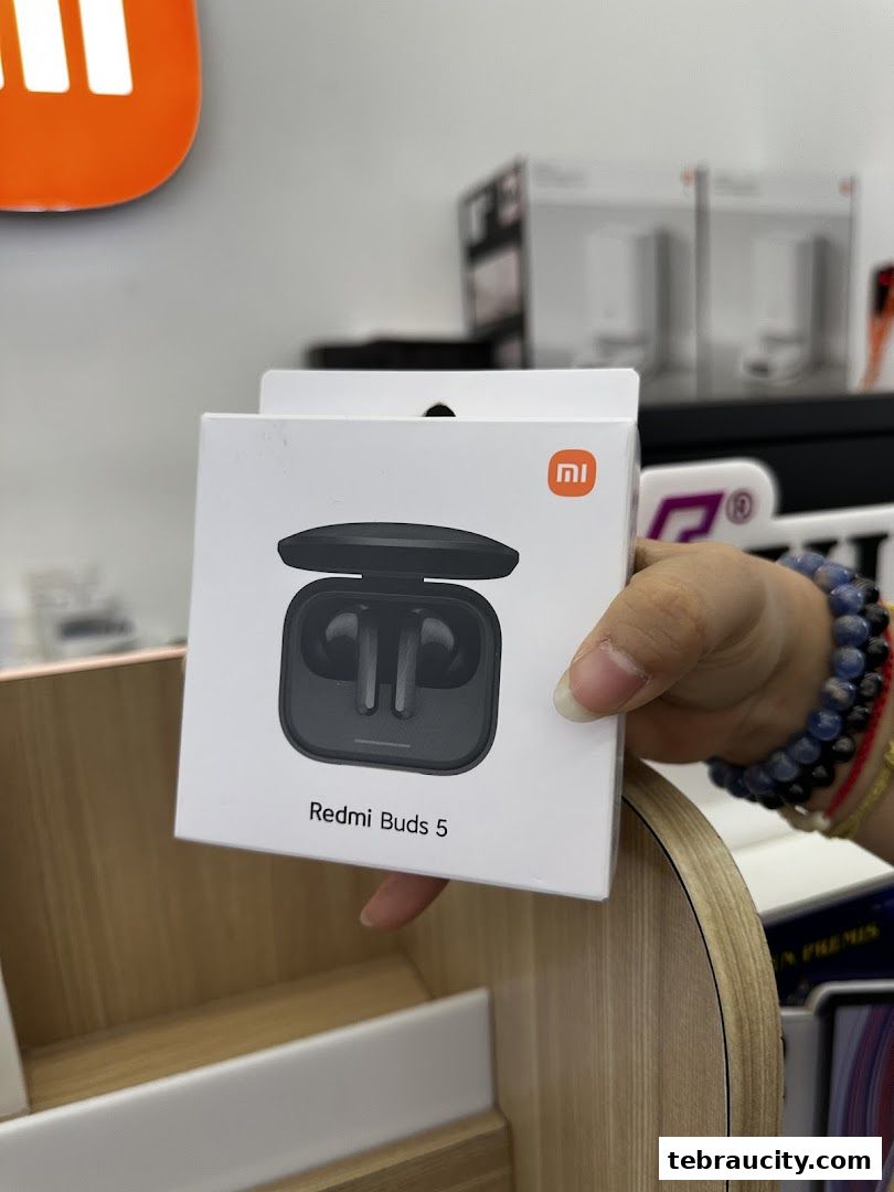 A hand holds a box of Redmi Buds 5 in a Xiaomi store.