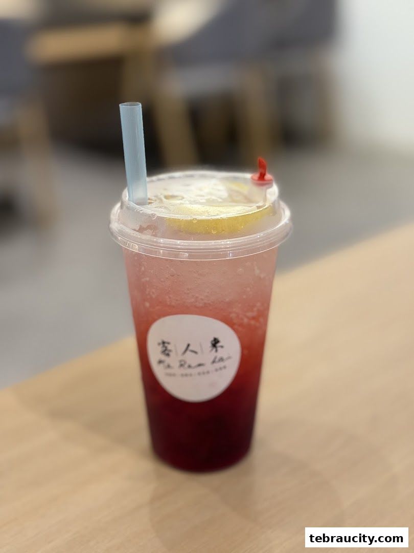 A refreshing beverage with lemon slices and a straw, featuring the shop's logo.