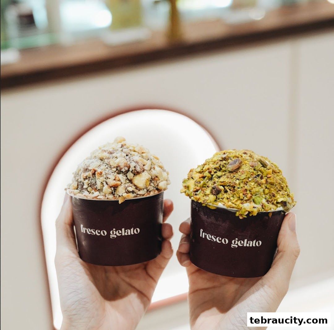 Two cups of gelato, one with nuts and the other with pistachios, held by hands.