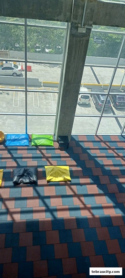 Colorful bean bags are arranged on a checkered floor with a view of a parking lot through large windows.