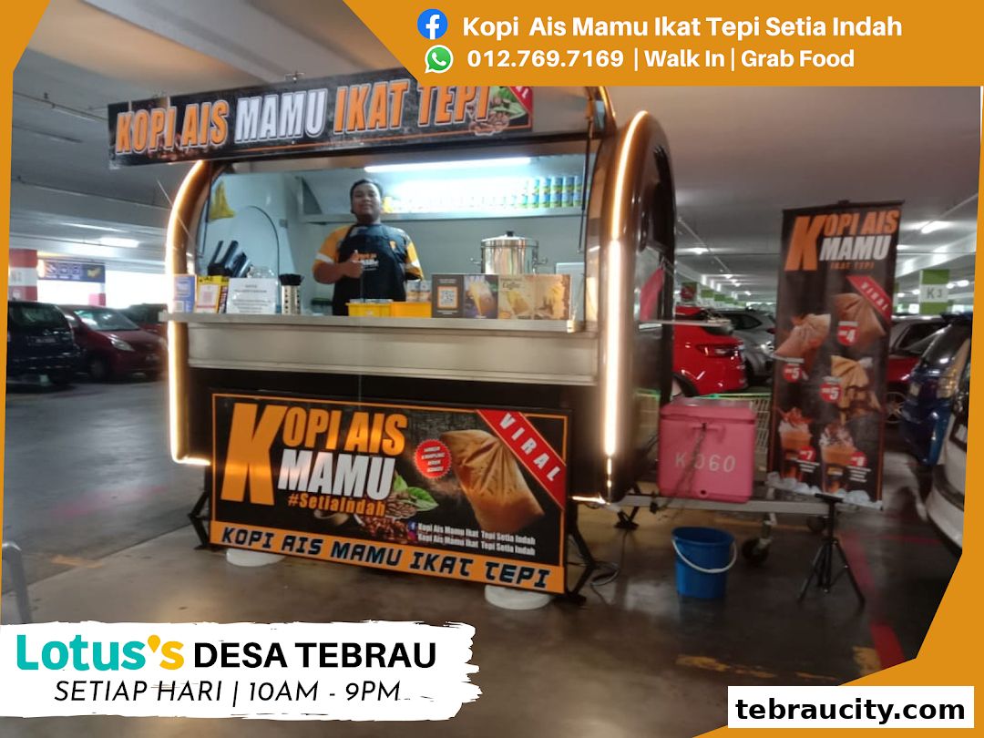 A mobile coffee stall with a vendor and promotional banners in a parking lot.