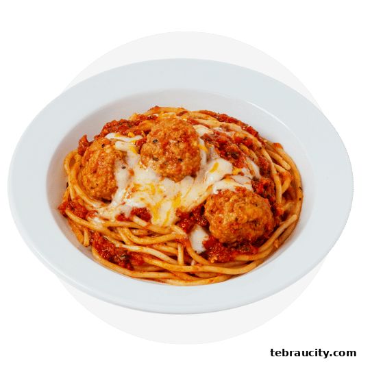 A close-up shot of spaghetti with meatballs and melted cheese in a white bowl.