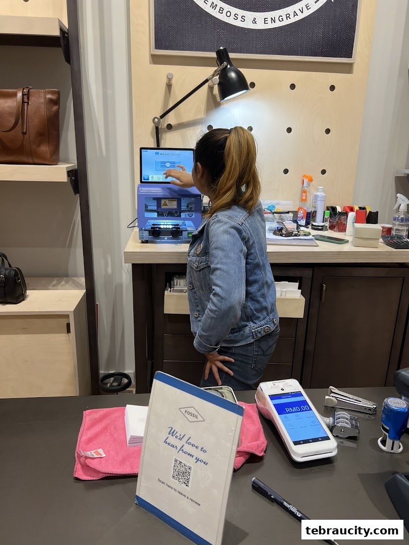 A woman operates an engraving machine at a Fossil store counter.