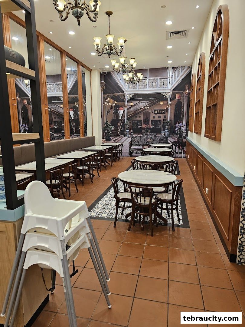 Interior of a Peranakan-themed restaurant with tables, chairs, and decorative wallpaper.