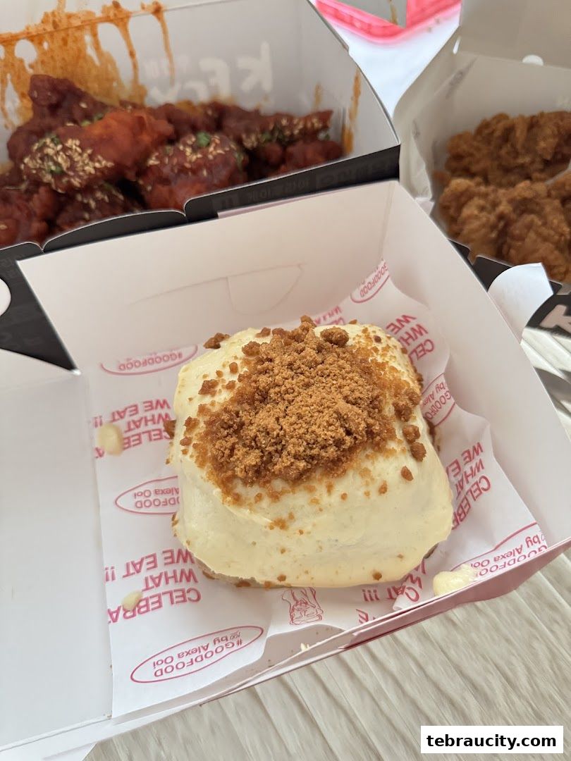A close-up of a sweet pastry with frosting and crumbs, next to boxes of fried chicken.