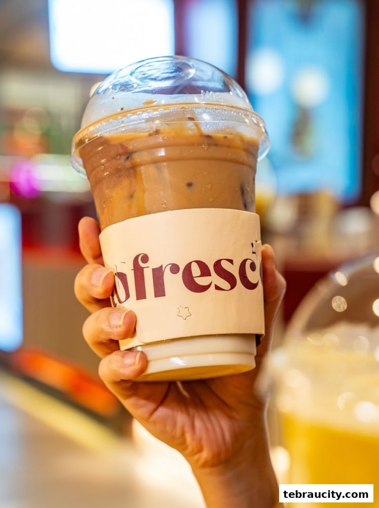 A hand holds a refreshing iced coffee with the Fresco Gelato logo.