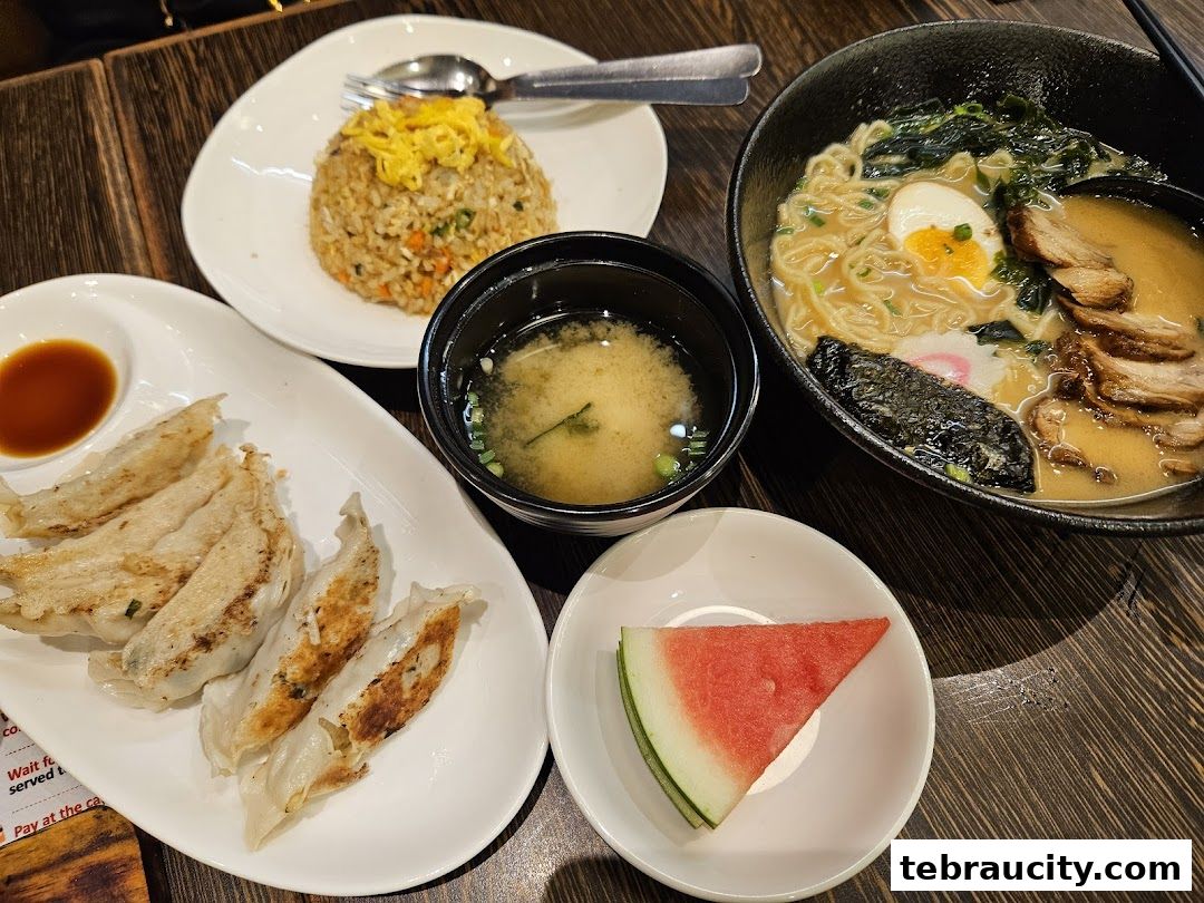 A delicious spread of Japanese food including ramen, gyoza, fried rice, and watermelon.