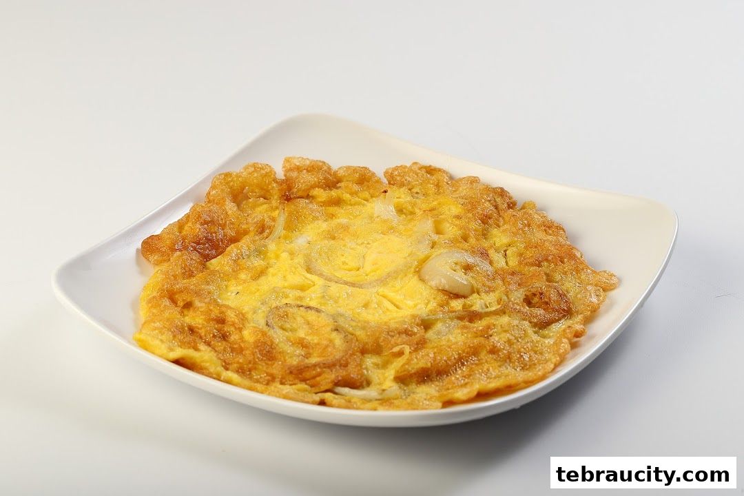 A close-up shot of a golden-brown omelet with visible onion slices on a white plate.