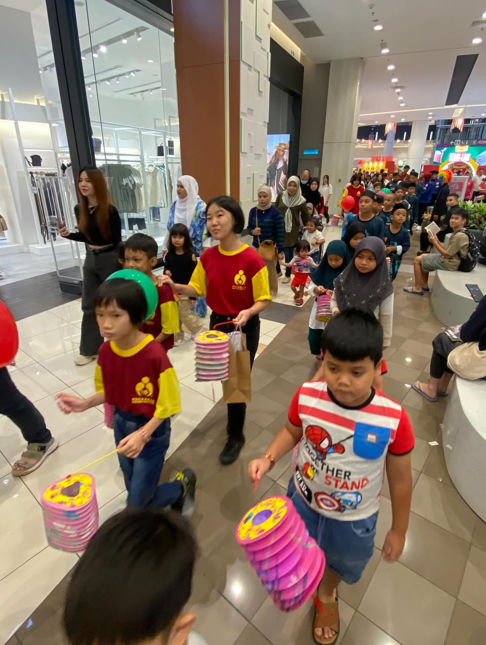 A group of children and families participating in the lantern parade at AEON Mall Tebrau City