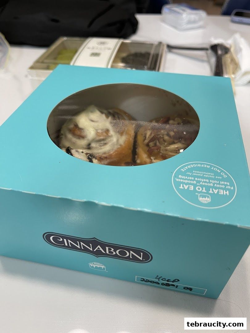 A box of Cinnabon cinnamon rolls with frosting and toppings.