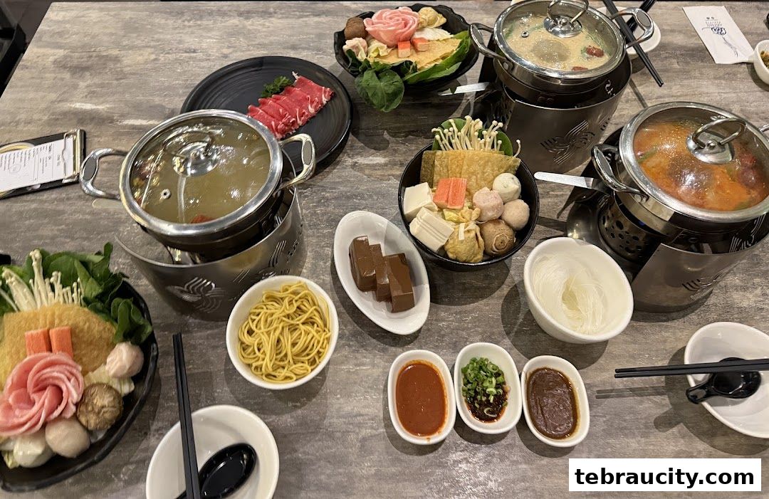 A table laden with various ingredients and dipping sauces for a shabu-shabu meal.