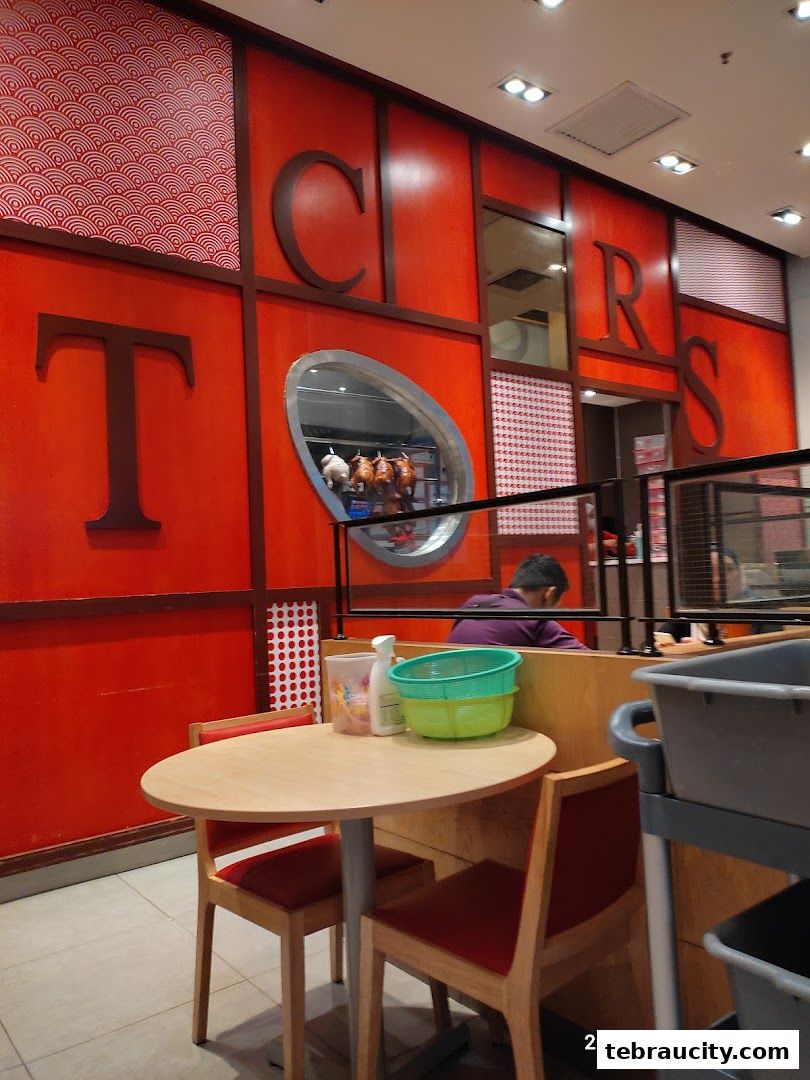 Interior of The Chicken Rice Shop with red walls, seating, and a display of roasted chickens.