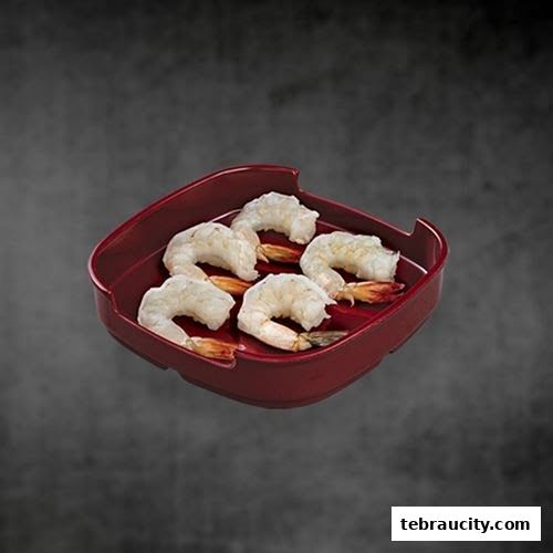 A red tray holds five fresh, raw shrimp on a dark, textured background.