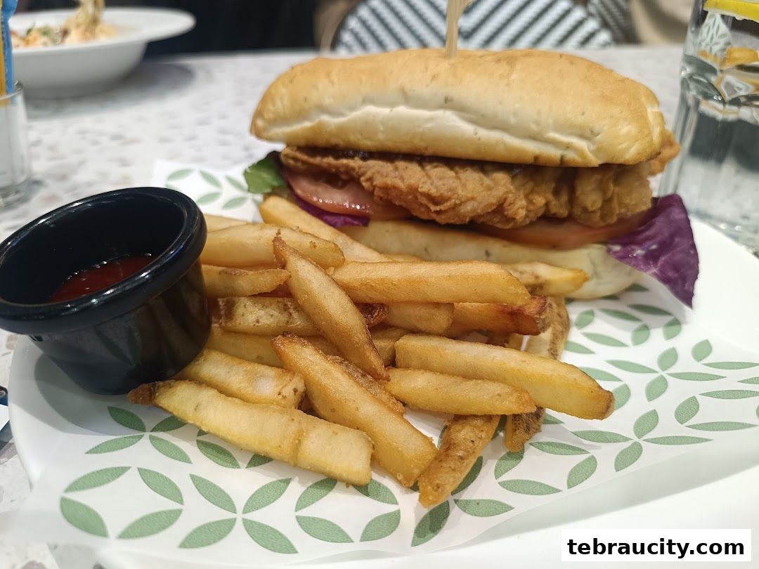 A delicious burger and fries served with a side of ketchup on a patterned plate.