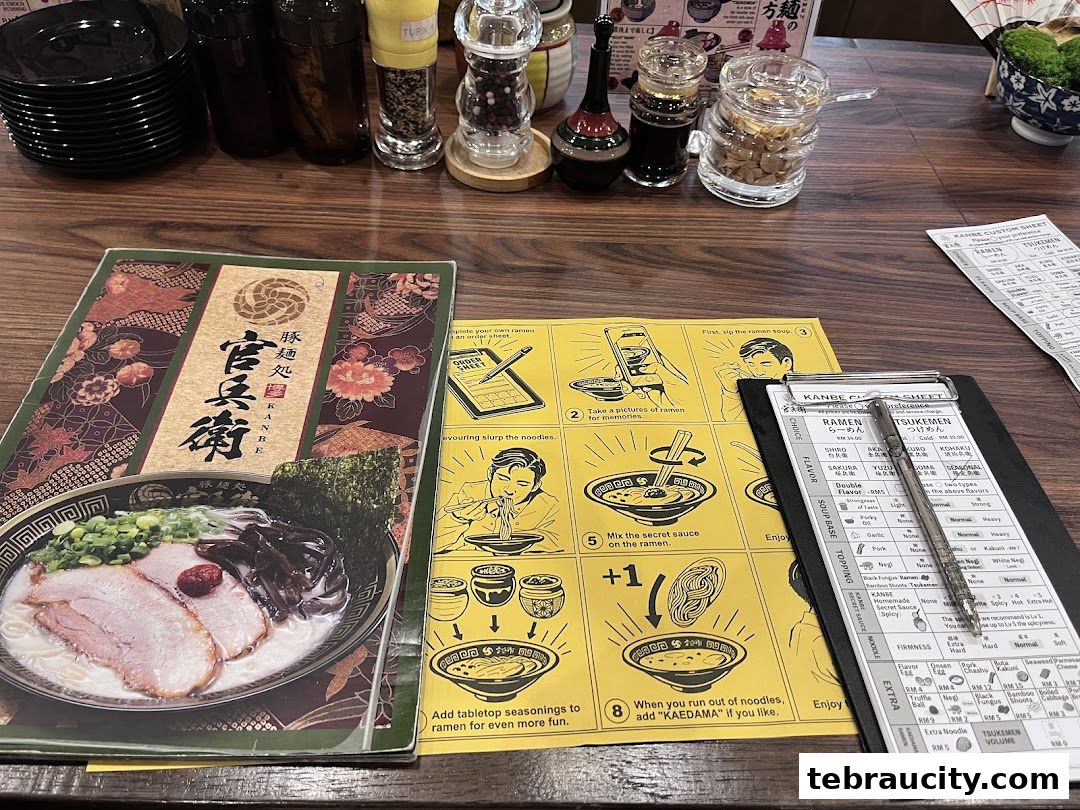 A table setting at a ramen restaurant with menus, order sheets, and condiments.