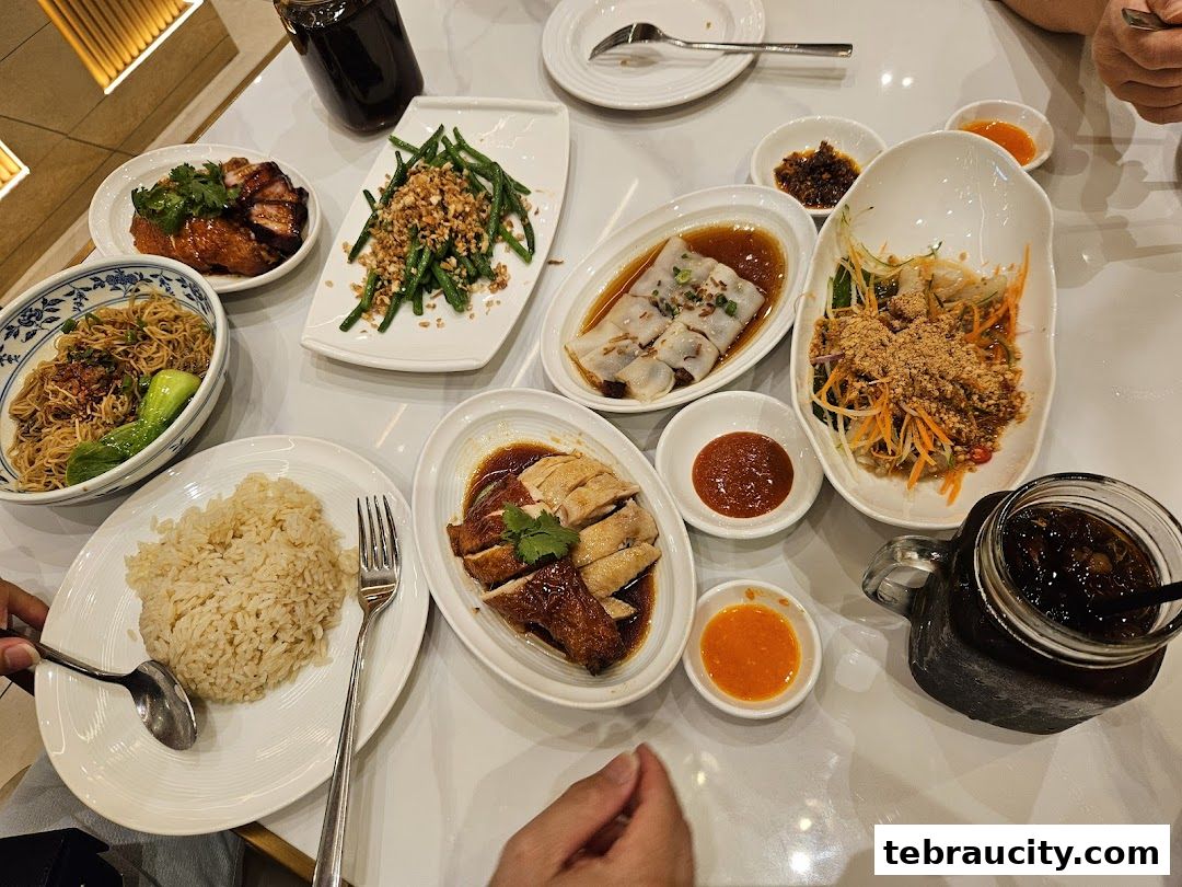 A table laden with various Hainanese chicken rice dishes and side orders.