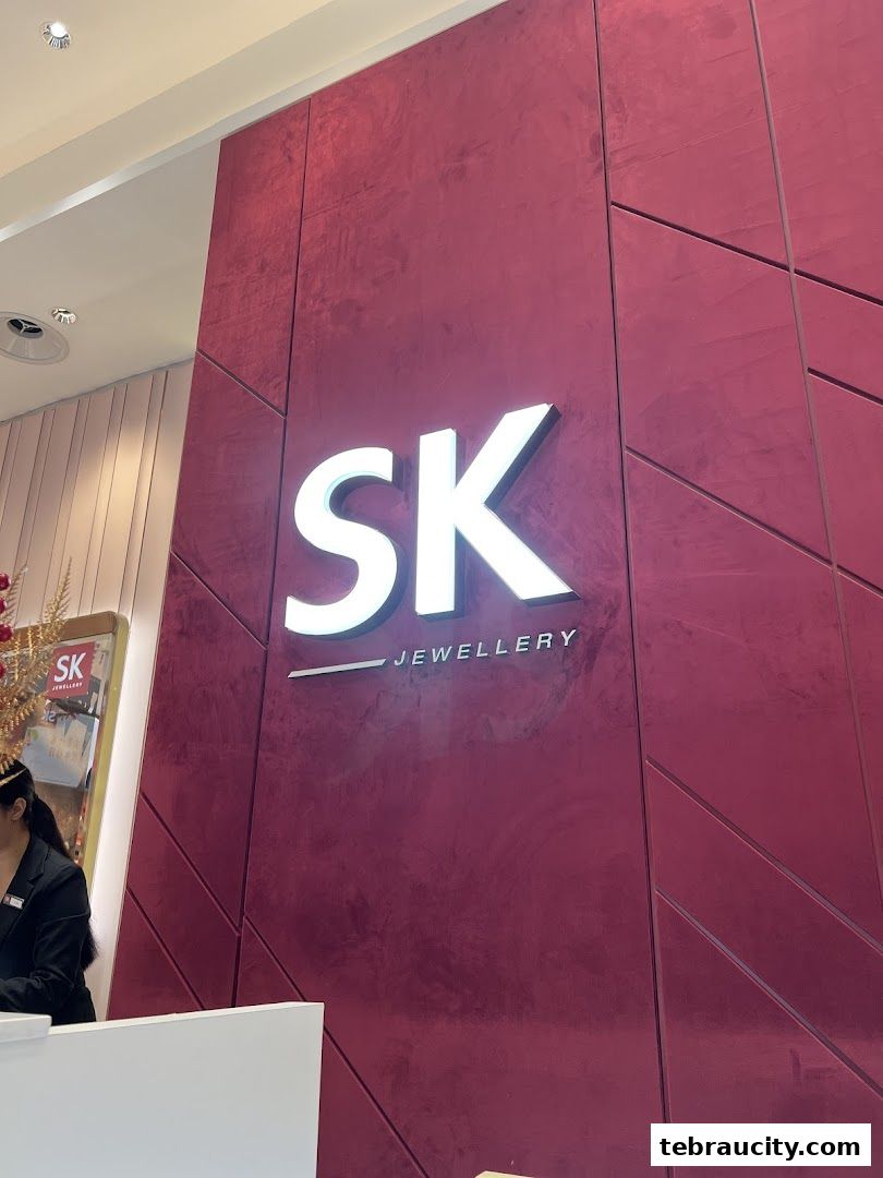 The illuminated SK Jewellery logo on a textured red wall.