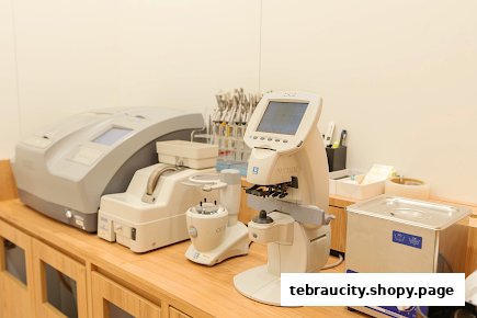 Optical equipment including lens edgers, focimeters, and ultrasonic cleaners on a wooden counter.